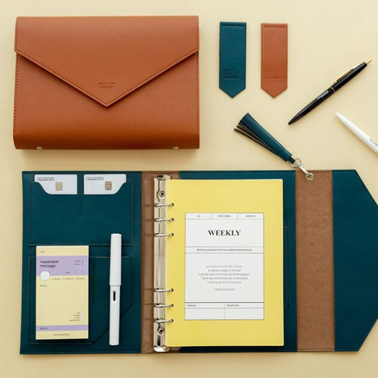 Organizational items including a brown envelope, planner, pen, and other stationery on a beige background